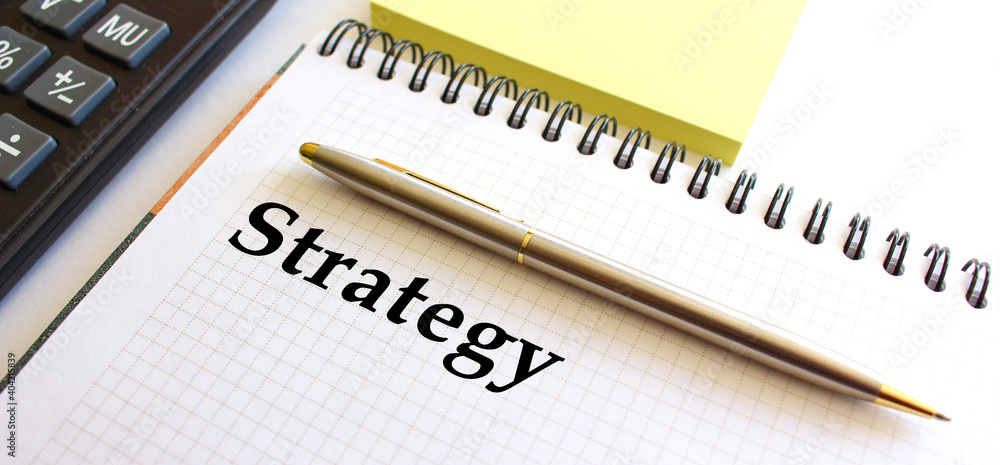 Notepad with text STRATEGY, next to it lies a calculator. Business concept. Notepad with text STRATEGY, next to it lies a calculator. Business concept.