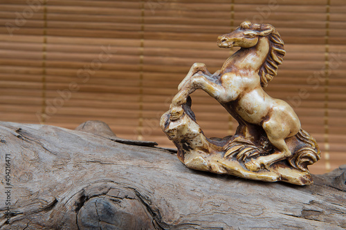 closeup of japanese netsuke figure on wooden and bamboo background. Statue horse mascot