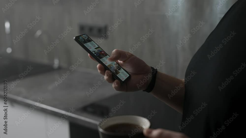 Male hands are holding a smartphone on which the application for the selection of used cars is open. A man chooses a car for himself via the Internet. Male hands are holding a smartphone on which the application for the selection of used cars is open. A man chooses a car for himself via the Internet.
