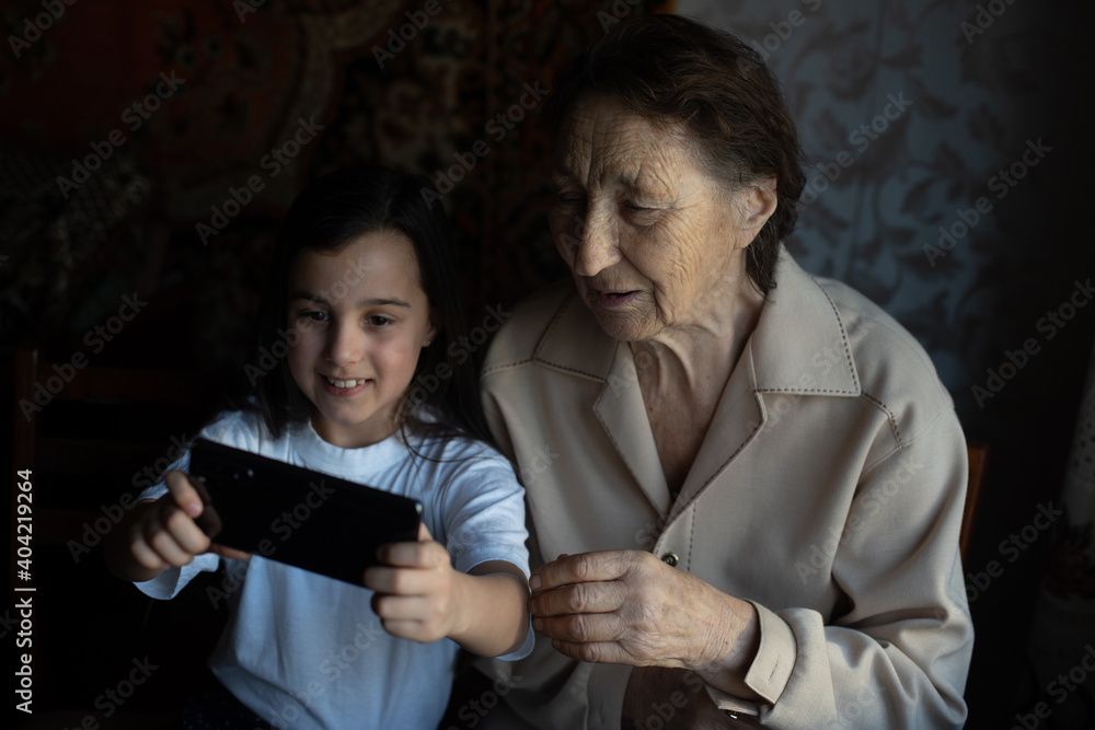 very old great-grandmother and granddaughter with a smartphone online very old great-grandmother and granddaughter with a smartphone online