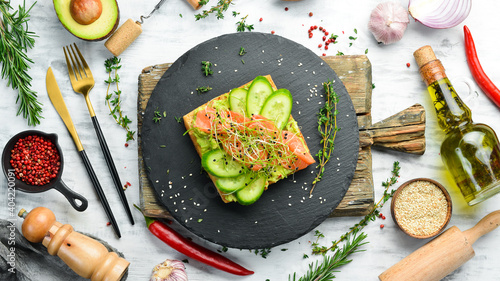 Sandwich. Fresh piece of ciabatta with avocado hummus and salted red fish. On a black stone plate.