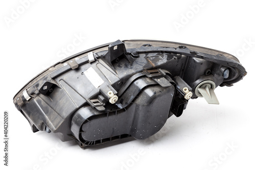 Spare part made of black plastic, rear view on white background in a photo studio for a catalog - a xenon headlight inside electrical systems and optical equipment assemblies of a lamp and reflectors