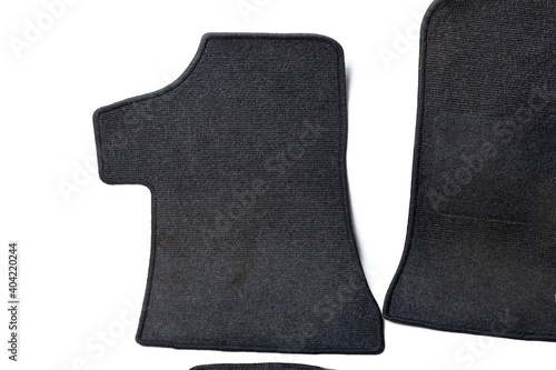 Close-up on a car floor mat in the back of a minivan made of black carpet on a white isolated background. Auto service industry. Spare parts catalog.