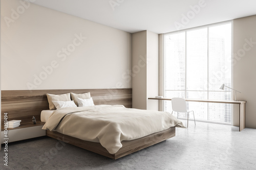 Beige bedroom, bed with linens and desk with chair near window © ImageFlow