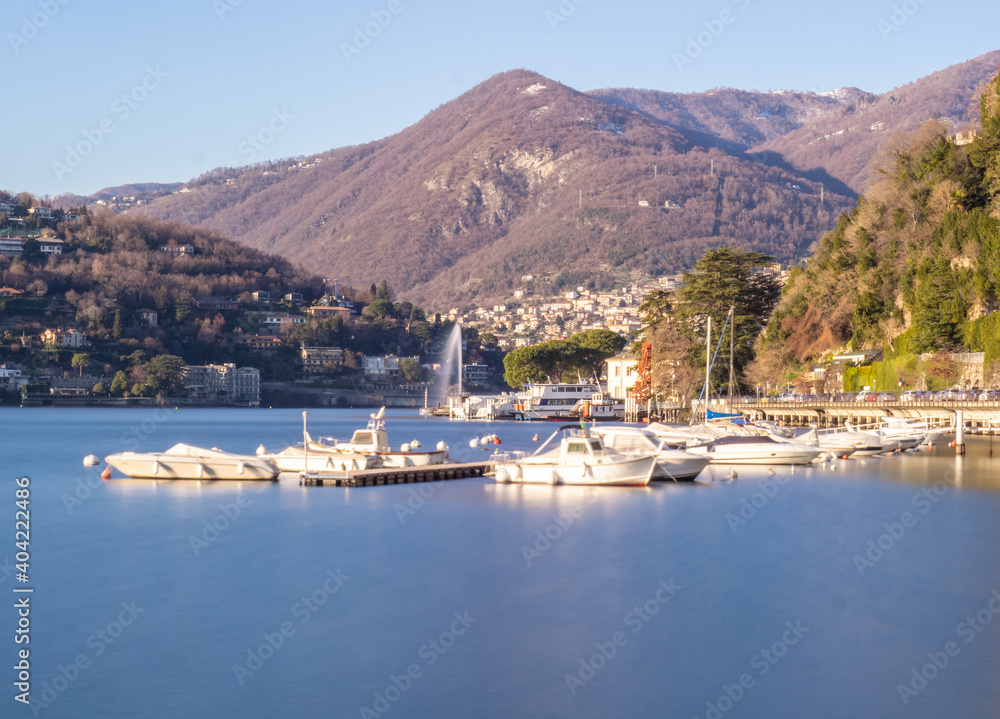 wide shot with boats moored on Lake Como on a colorful sunny winter day. Italian lakes, Lombardy, Italy