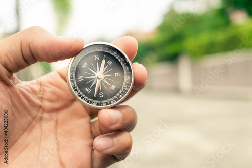 Man hand holding compass on city and car blurred background Using wallpaper or background travel or navigator image.