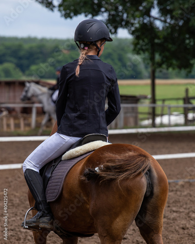 Young girl riding on a horse in an event.