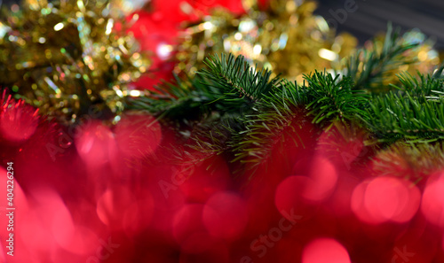 Christmas background with gold tinsel and red blurred lights  green spruce branches.