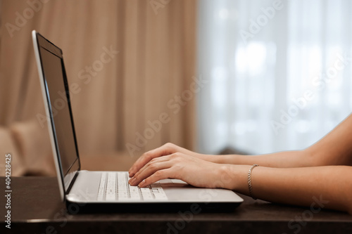 The hard hands of a businessman are typing on a laptop keyboard against the background of a blurred room. Concept for workplace, office, coworking, business, finance.