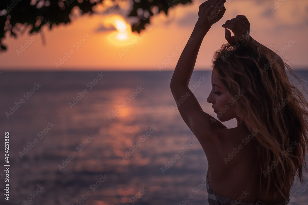 Young beautiful woman relaxing on the sea shore at sunset enjoying nature and travel