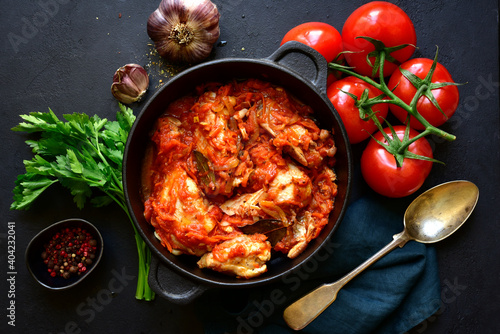 Chakhokhbili - traditional dish of georgian cuisine. Chicken stewed with vegetables : carrot, onion, tomatoes in skillet. Top view with copy space.