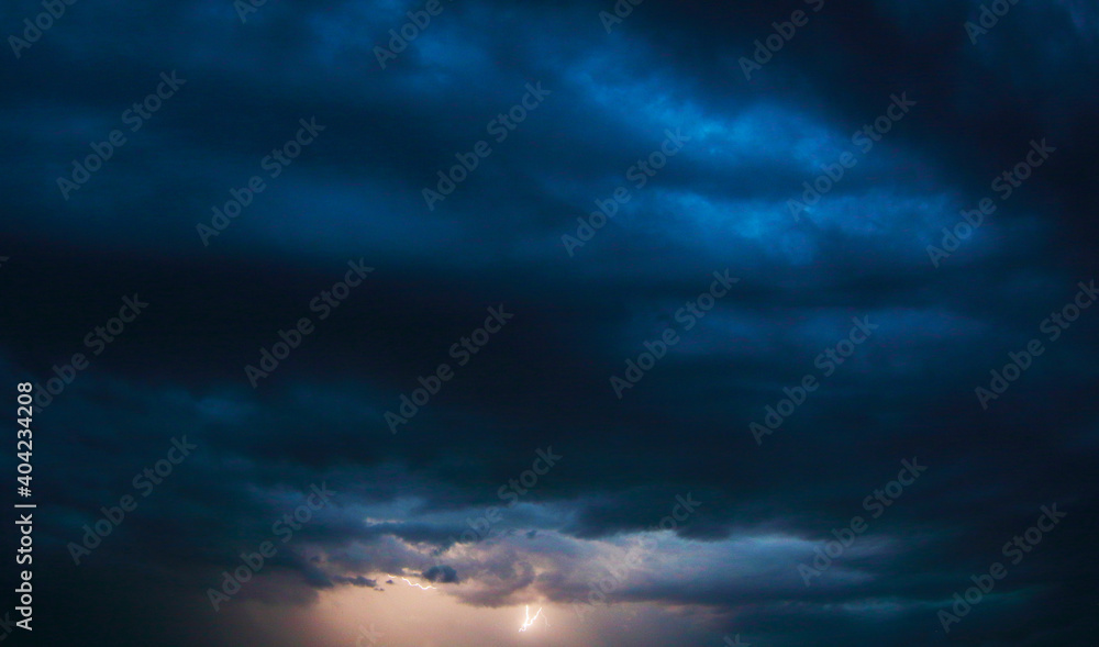 Stormy sky during a thunderstorm. Thunderous flash on the horizon of a dark blue sky. For background wallpapers and postcards.