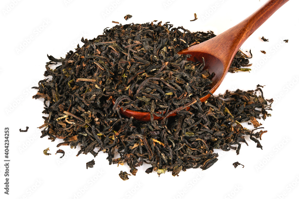 Black loose dry tea from Assam, India with brown spoon. Close-up macro isolated on white background top view. Black loose dry tea from Assam, India with brown spoon. Close-up macro isolated on white background top view.