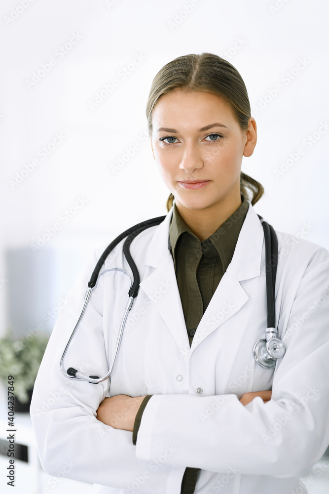 Woman-doctor standing with arms crossed and looking at camera. Perfect medical service in clinic. Medicine and healthcare Woman-doctor standing with arms crossed and looking at camera. Perfect medical service in clinic. Medicine and healthcare
