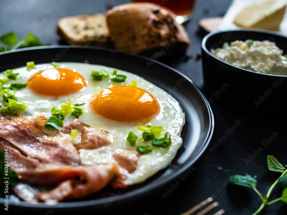 Continental breakfast - sunny side up eggs on bacon on wooden table Continental breakfast - sunny side up eggs on bacon on wooden table