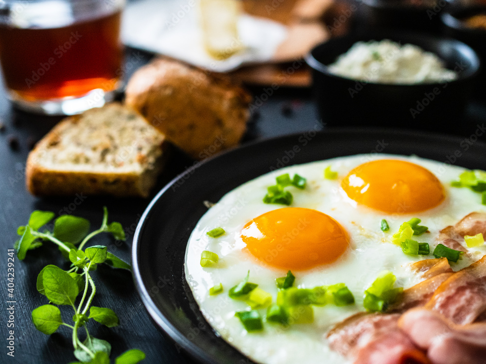 Continental breakfast - sunny side up eggs on bacon on wooden table Continental breakfast - sunny side up eggs on bacon on wooden table