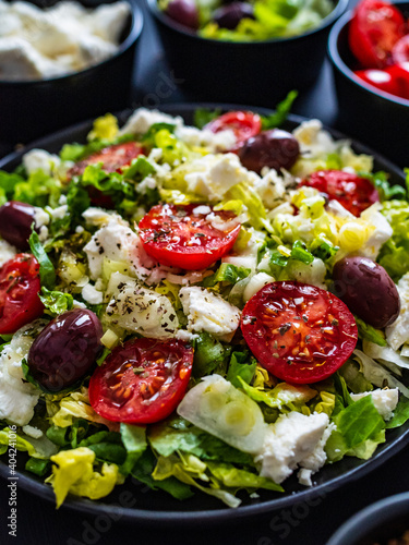 Fresh Greek salad - feta cheese, tomatoes, cucumber, lettuce, black olives and onion on wooden table