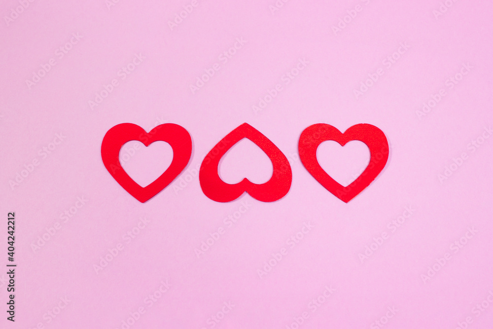 Symbol of love. Three hearts on a pink background. Top view.