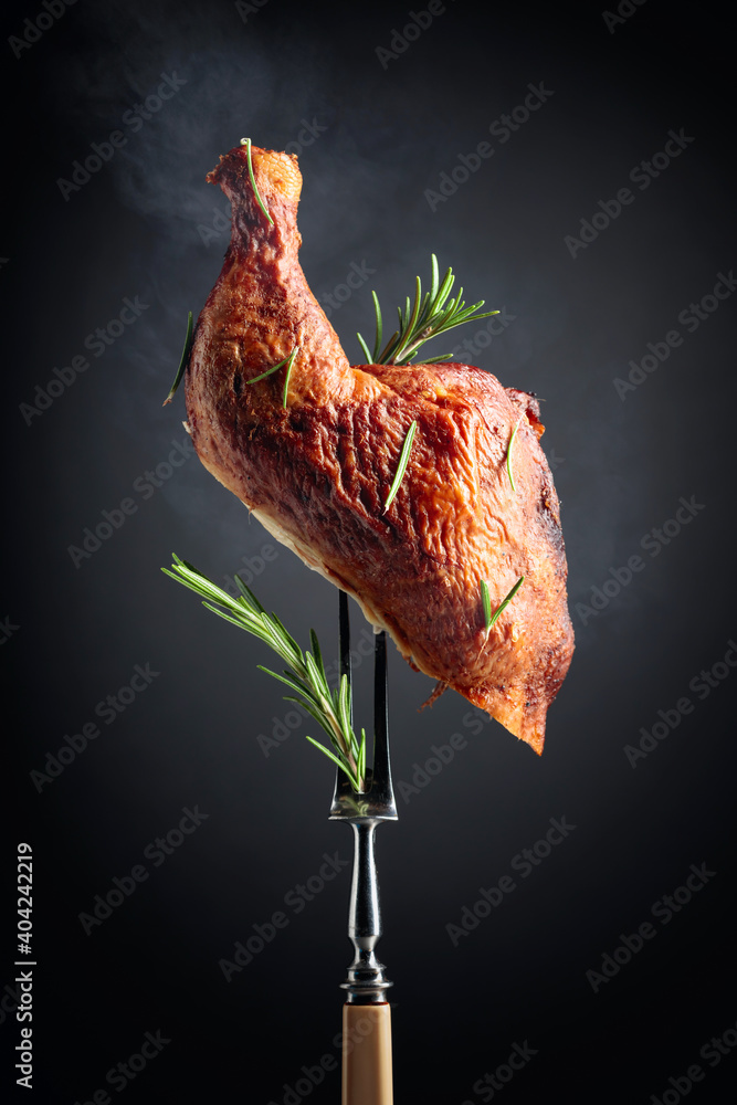 Smoked chicken thigh on a fork sprinkled with rosemary. - obrazy, fototapety, plakaty 
