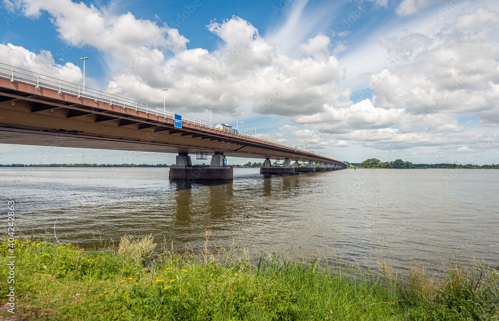 Moerdijk road bridge over the Hollandsch Diep river seen from the southern bank in the province of Noord-Brabant. The photo was taken on a sunny day in the summer season. Moerdijk road bridge over the Hollandsch Diep river seen from the southern bank in the province of Noord-Brabant. The photo was taken on a sunny day in the summer season.