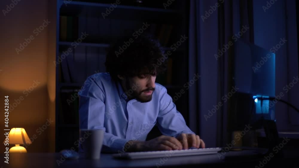 Tired exhausted freelancer watching monitor and working typing on wireless keyboard at late night. Concept of remote working, distance learning, self-employment during coronavirus quarantine. Tired exhausted freelancer watching monitor and working typing on wireless keyboard at late night. Concept of remote working, distance learning, self-employment during coronavirus quarantine.