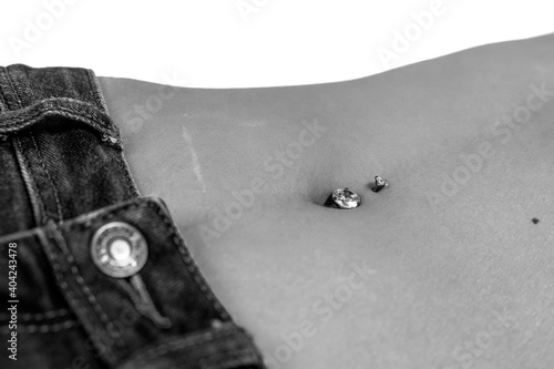 Belly button or navel piercing, of young woman wearing jeans isolated on white. Close-up macro shot. Dramatic monochrome, black and white photo. High quality image.