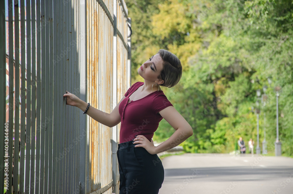 A girl stands on the street holding a metal fence