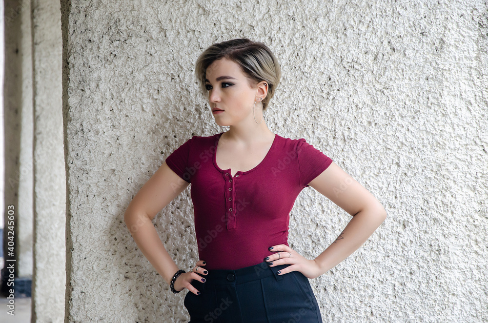 A girl in a red jacket stands against the background of a concrete column A girl in a red jacket stands against the background of a concrete column