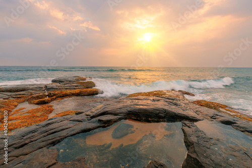 Beautiful seascape. Rocks and stones at the ocean coast under a beautiful sunset sky with clouds on Sri Lanka island.