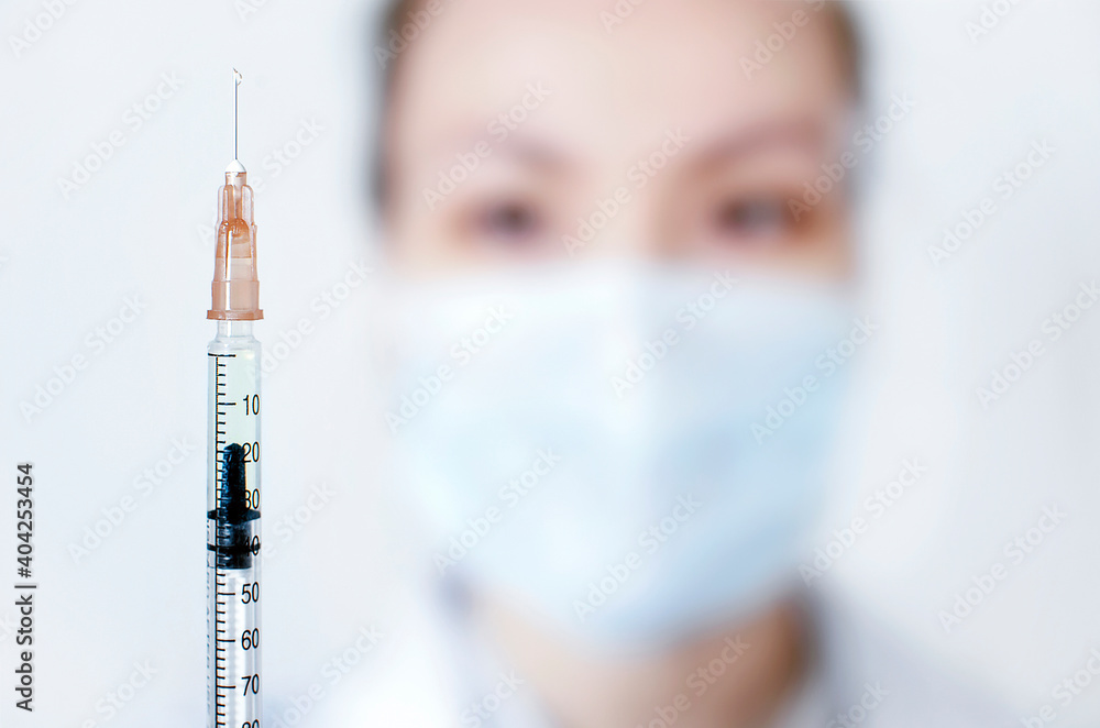 Insulin syringe with medicine close-up on the background of the nurse's face. Focus on the foreground Insulin syringe with medicine close-up on the background of the nurse's face. Focus on the foreground