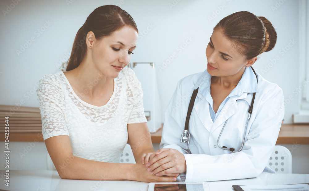 Woman-doctor reassuring her female patient while sitting at the desk. Medicine concept Woman-doctor reassuring her female patient while sitting at the desk. Medicine concept
