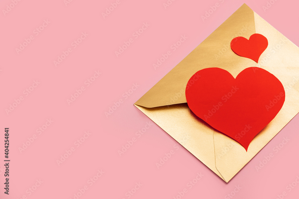 Golden paper envelope with two red hearts isolated on pink background