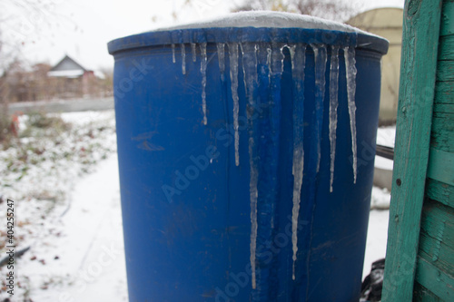 blue barrel in the garden with frozen ice with icicles