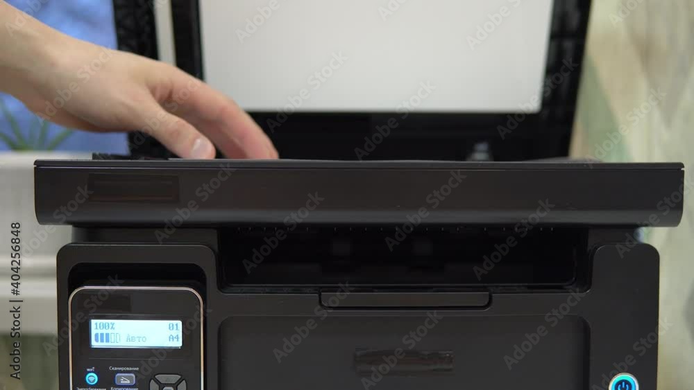 A man puts a document on the scanner to scan and tries to start A man puts a document on the scanner to scan and tries to start