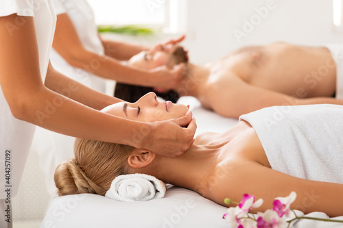 Relaxed Spouses Receiving Face Massage Together Lying On Beds Indoors