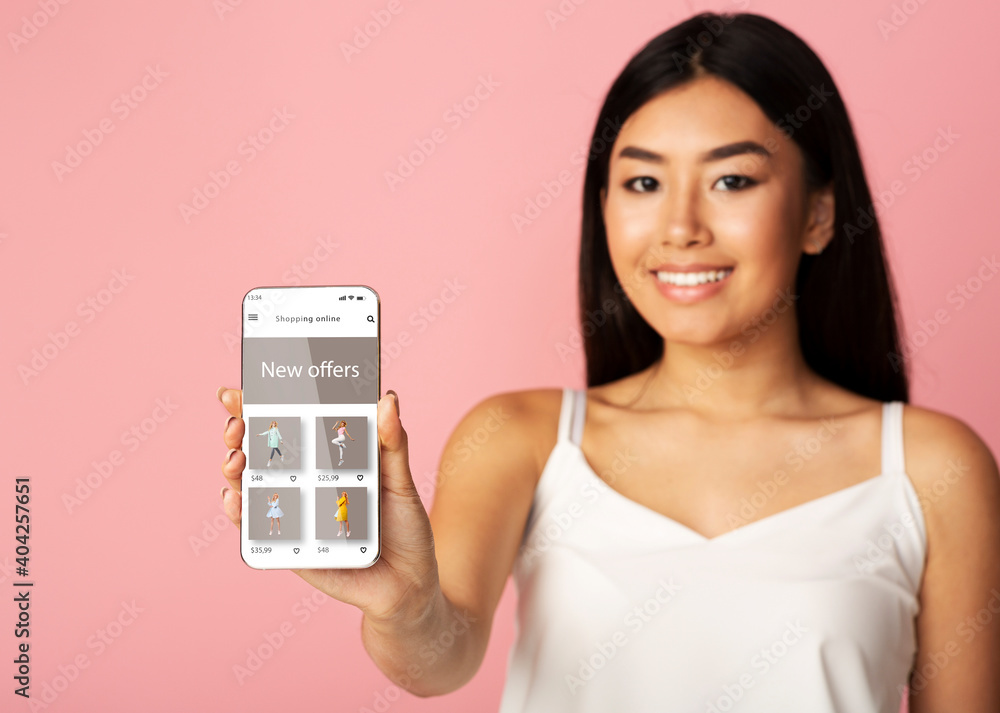 Asian lady showing phone with online fashion store website Asian lady showing phone with online fashion store website