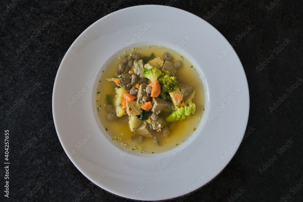 Ein weißer Teller Gemüsesuppe, Hühnersuppe mit Karotten, Leberknödel und Bio Gemüse, Produktbild Ein weißer Teller Gemüsesuppe, Hühnersuppe mit Karotten, Leberknödel und Bio Gemüse, Produktbild