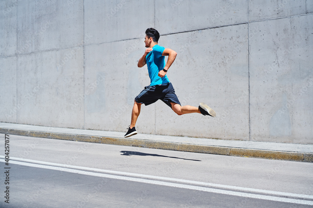 Fototapeta premium Athletic man sprinting running on city street