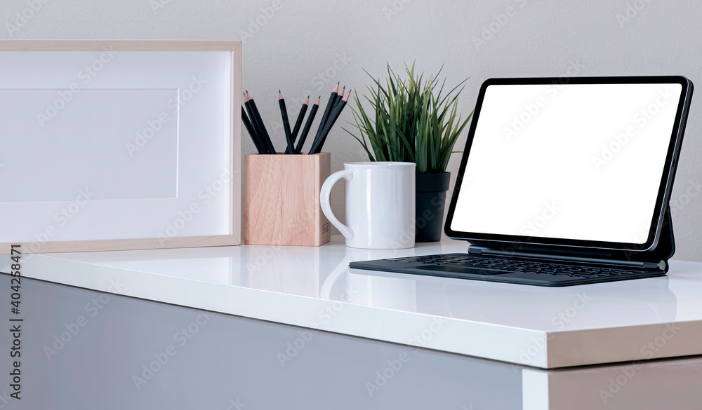 Fototapeta premium Mockup creative workspace with blank screen tablet and magic keyboard on white table in modern room.