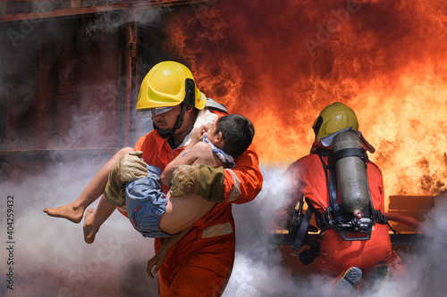 Firefighter holding child boy to save him in fire and smoke,Firemen rescue the boys from fire. photo