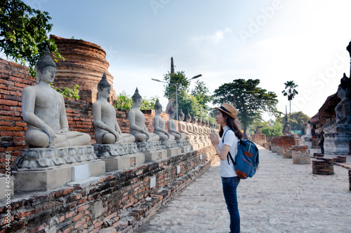 Asian woman tourists carrying a backpack and wearing a hat Visit Wat Yai Chaimongkol, the historical archaeological site of Phra Nakhon, Ayutthaya.