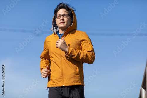 Young Asian Man running by the railway track outdoors in morning.