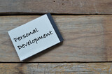Top view of notebook written with text PERSONAL DEVELOPMENT over wooden background. 