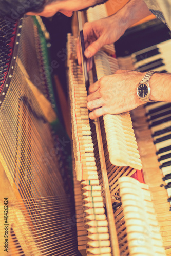 Piano tuning process. closeup of hand and tools of tuner working on grand piano. Detailed view of Upright Piano during a tuning. toned. toned. vertical photo. toned