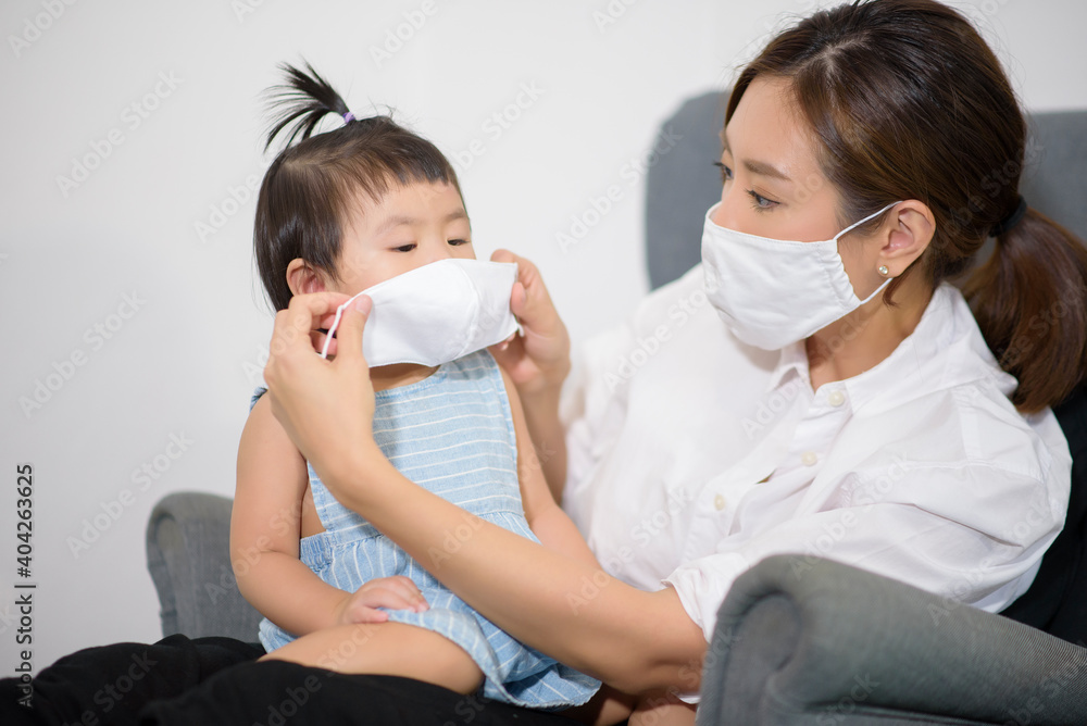 Mom and daughter are wearing protective mask , safety in home , covid-19 protection , healthy at home concept