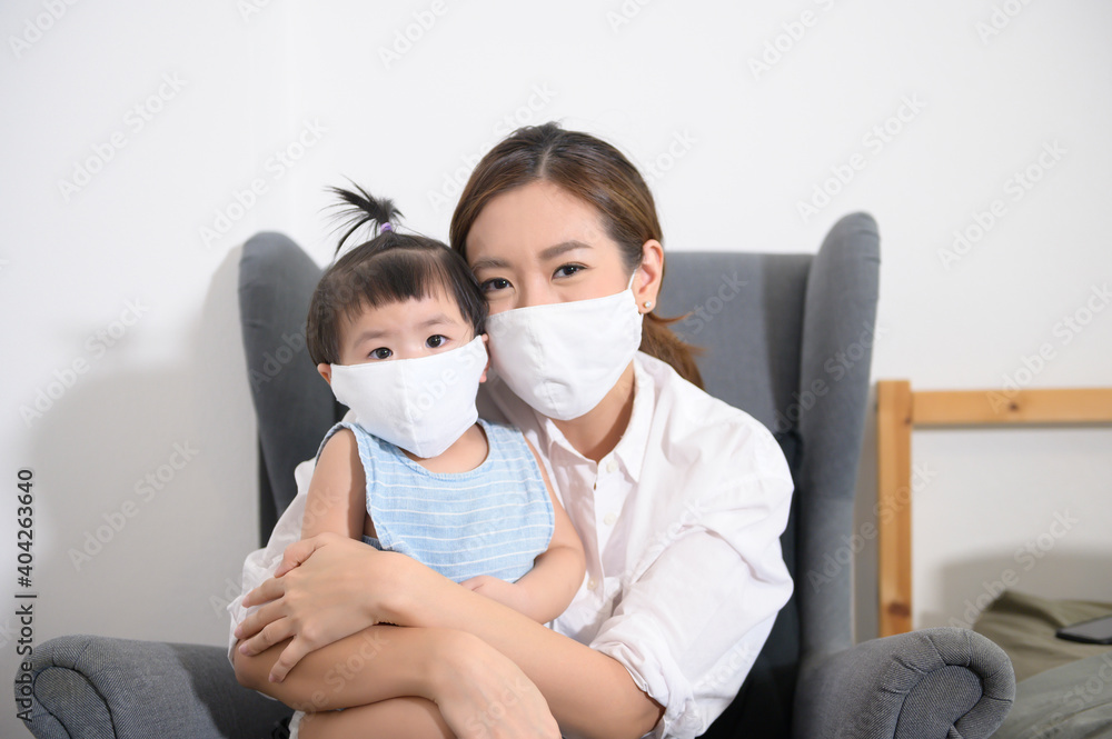 Mom and daughter are wearing protective mask , safety in home , covid-19 protection , healthy at home concept Mom and daughter are wearing protective mask , safety in home , covid-19 protection , healthy at home concept