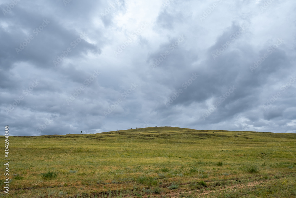 Scenic view of beautiful green hills and mountains with stormy cloudy sky on Olkhon island, Russia. Copy space.