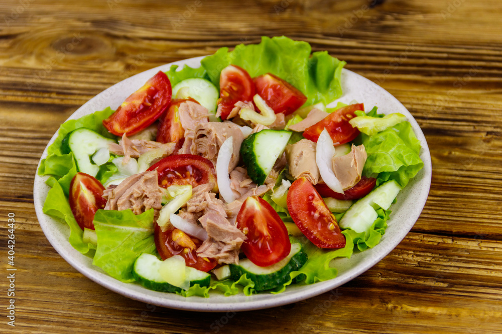 Tasty tuna salad with lettuce and fresh vegetables on wooden table