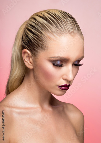 Beautiful young woman with bare shoulders cosmetics burgundy lips charm model pink background.