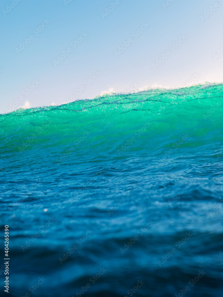 Perfect surfing wave in sea. Breaking turquoise wave with sun light